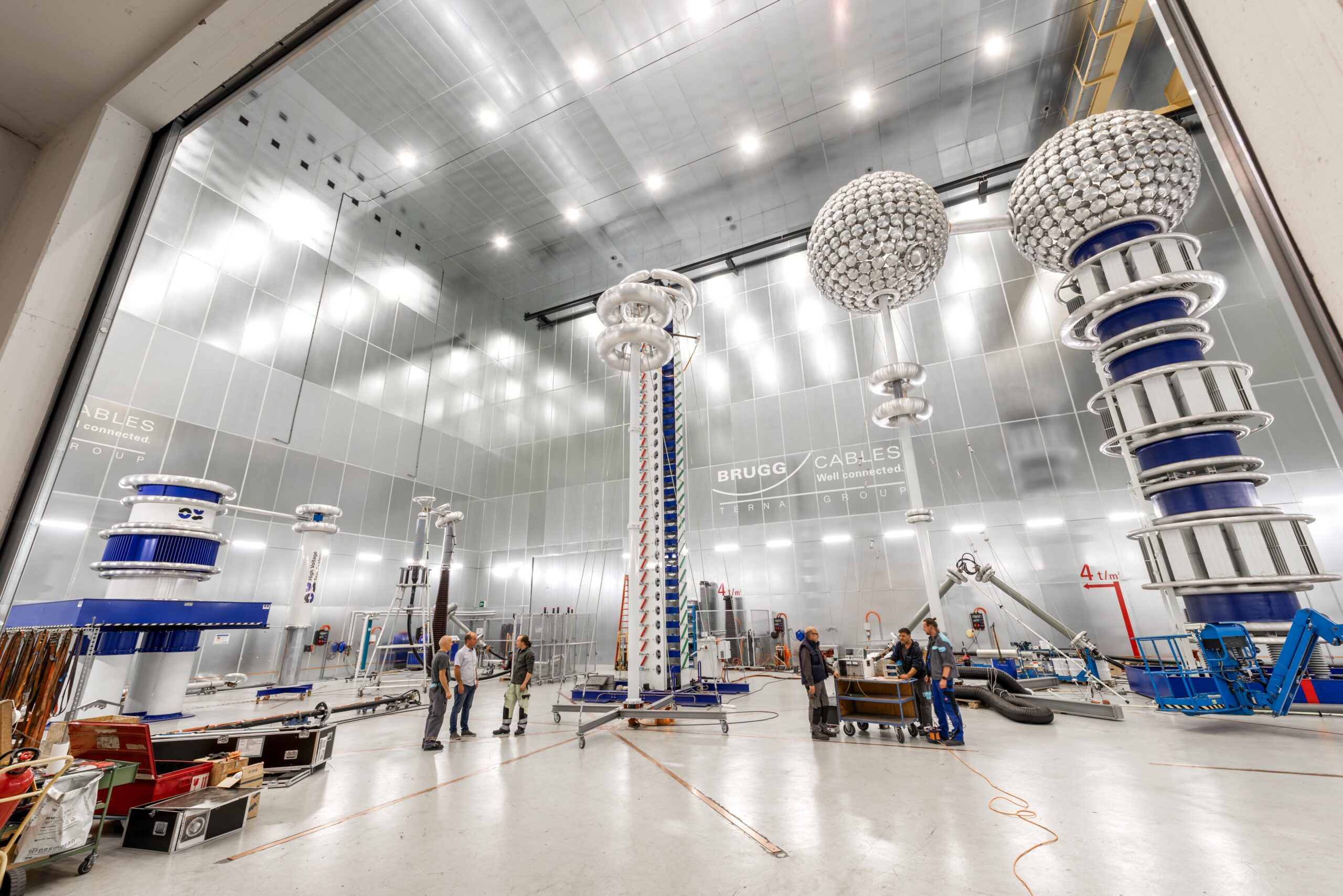 High‑voltage test hall with advanced Brugg Cables equipment and technicians at work.