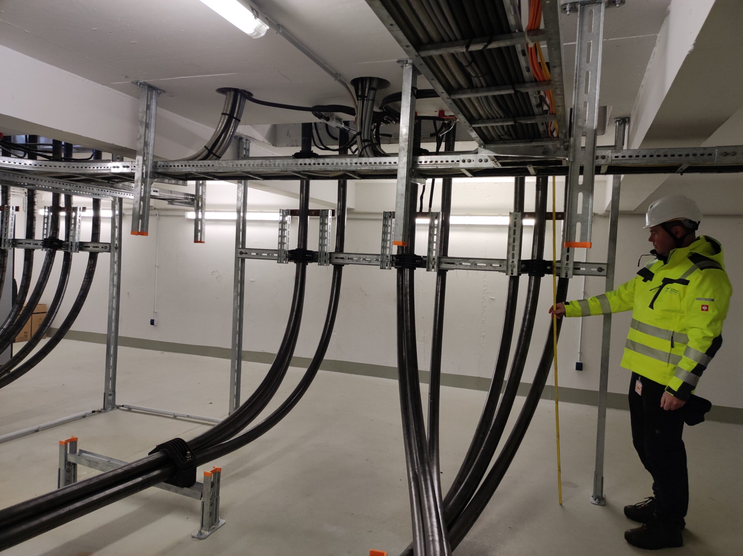 Brugg Cables engineer inspecting medium voltage cable routing and tray installation in indoor substation
