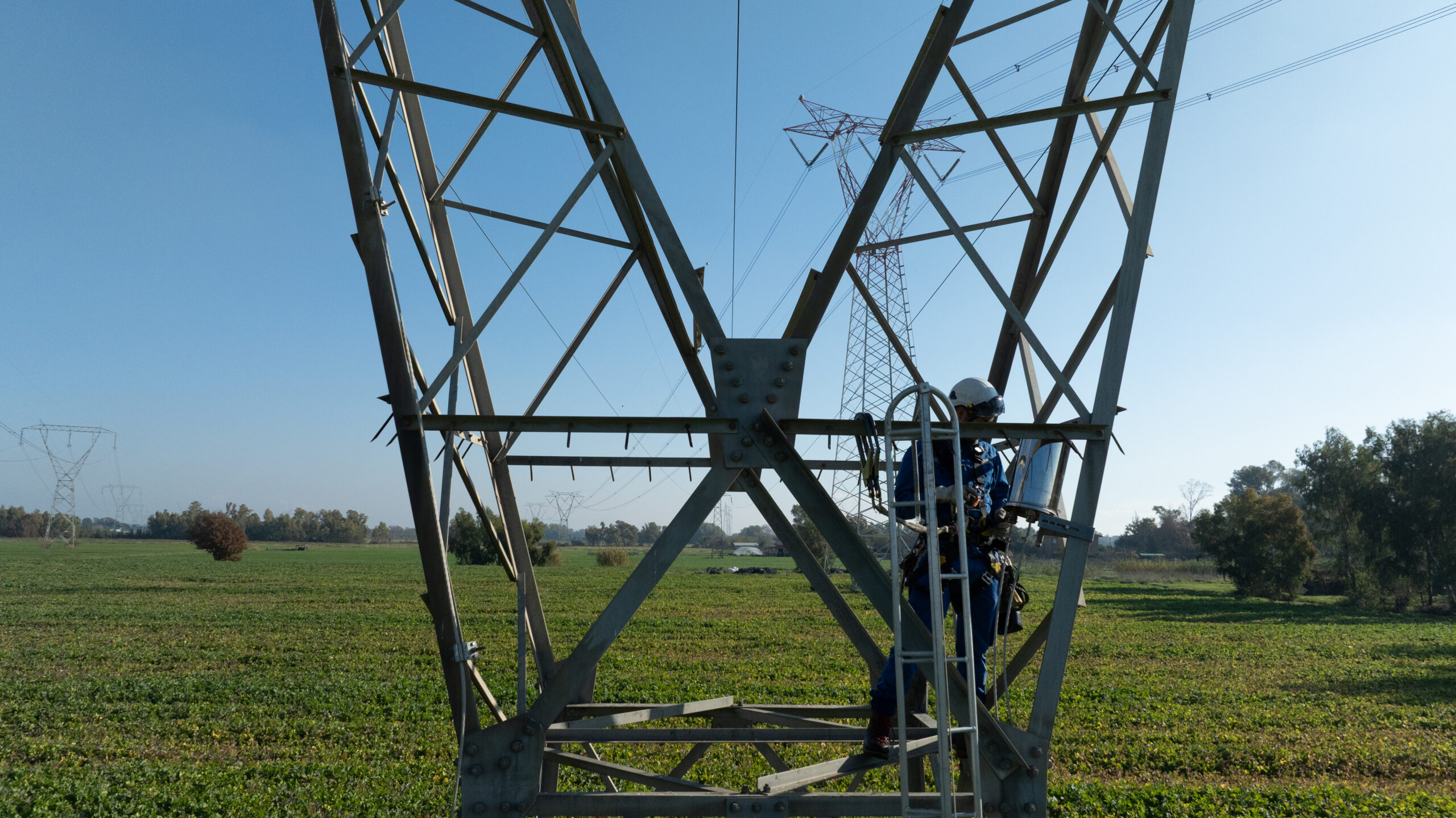 Technician performing maintenance on a high-voltage transmission tower as part of Brugg Cables infrastructure work
