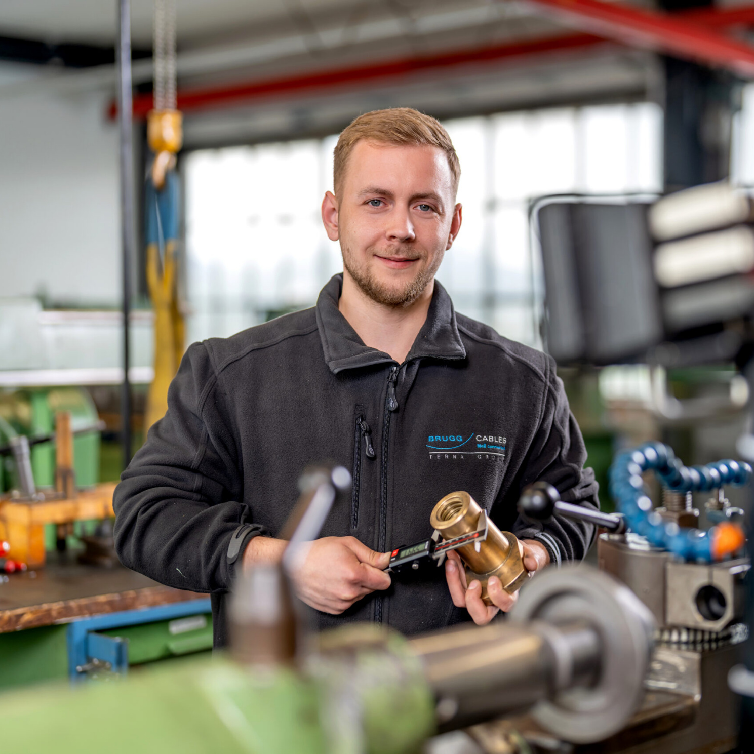 Brugg Cables technician measuring a cable component in the manufacturing workshop Brugg Cables technician measuring a cable component in the manufacturing workshop